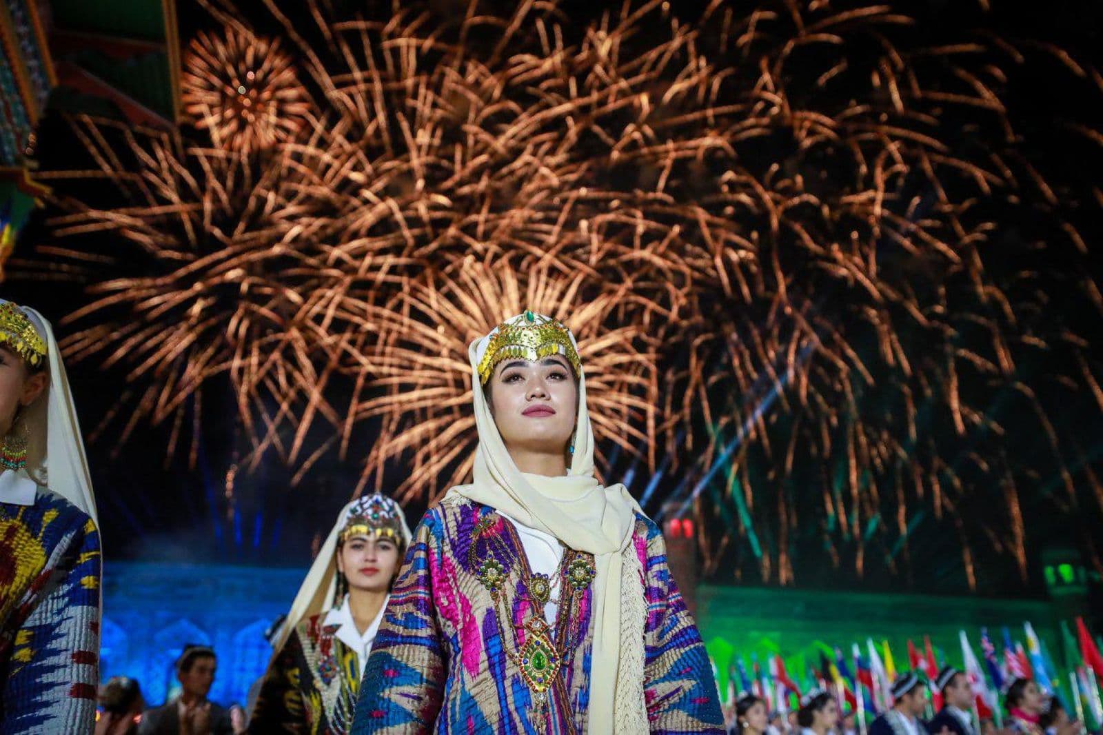 Dancers in traditional dress under festival fireworks