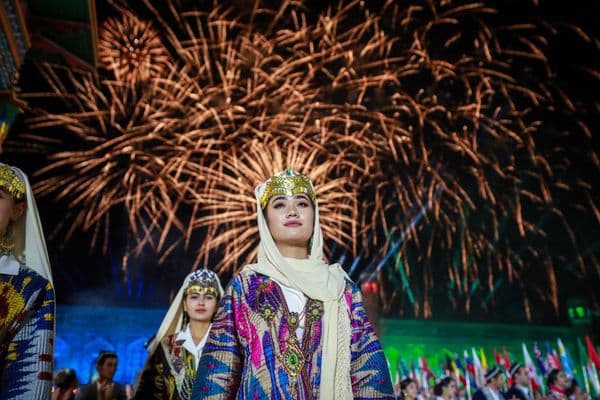 Dancers in traditional dress under festival fireworks