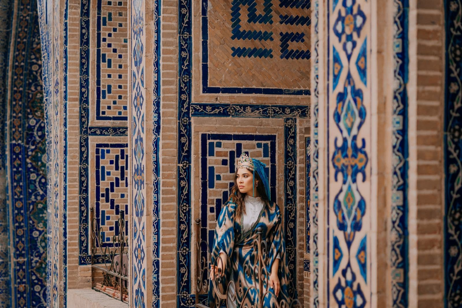 Woman in ikat robe at the tiled walls of Shah-i-Zinda