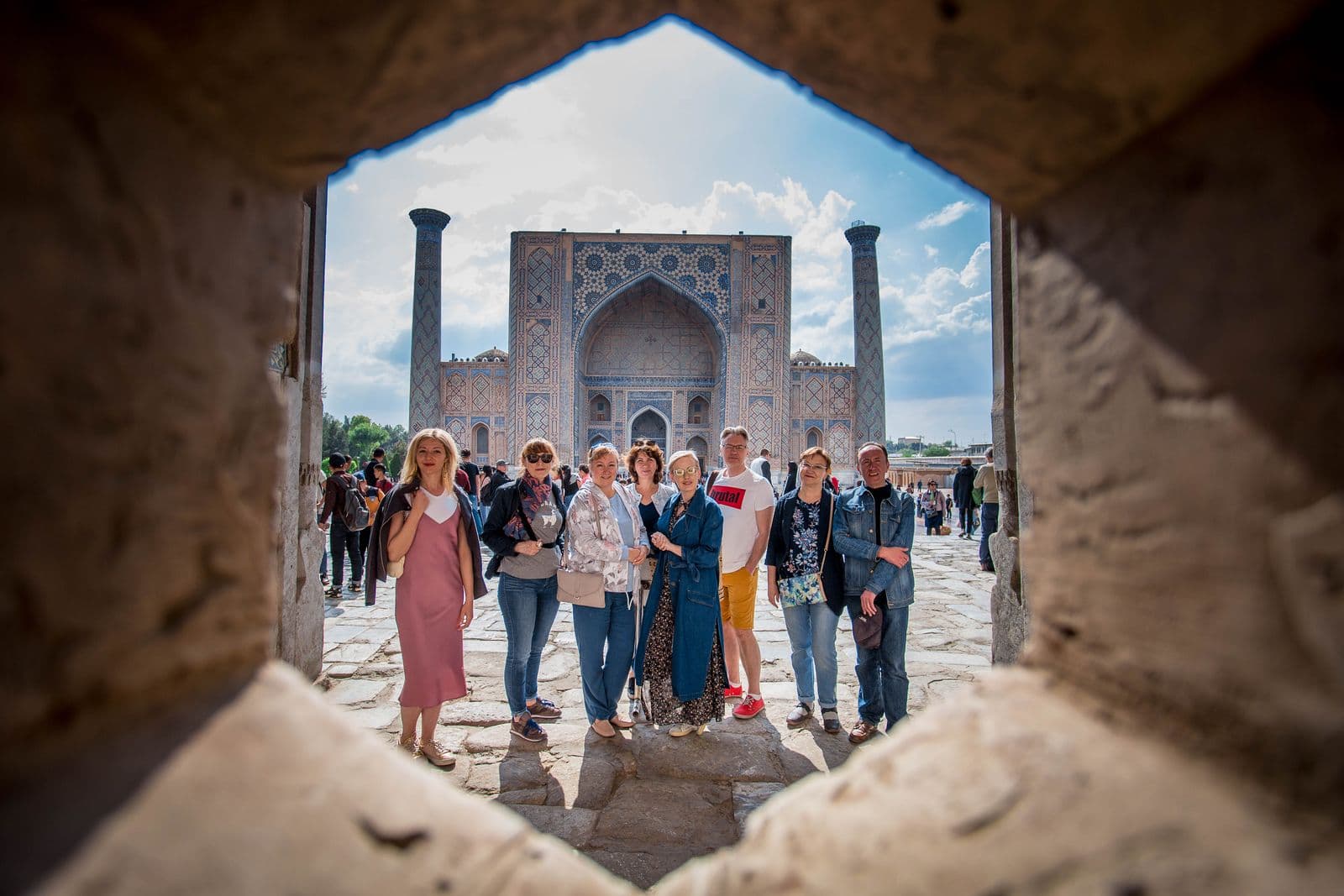 Family group at Registan Square through a stone arch